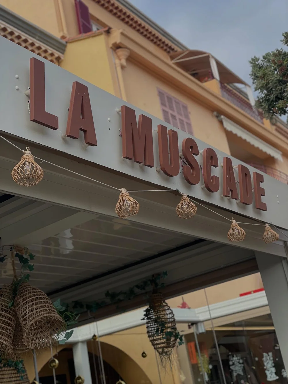 L'enseigne La Muscade, en lettres rouges au-dessus de la terrasse